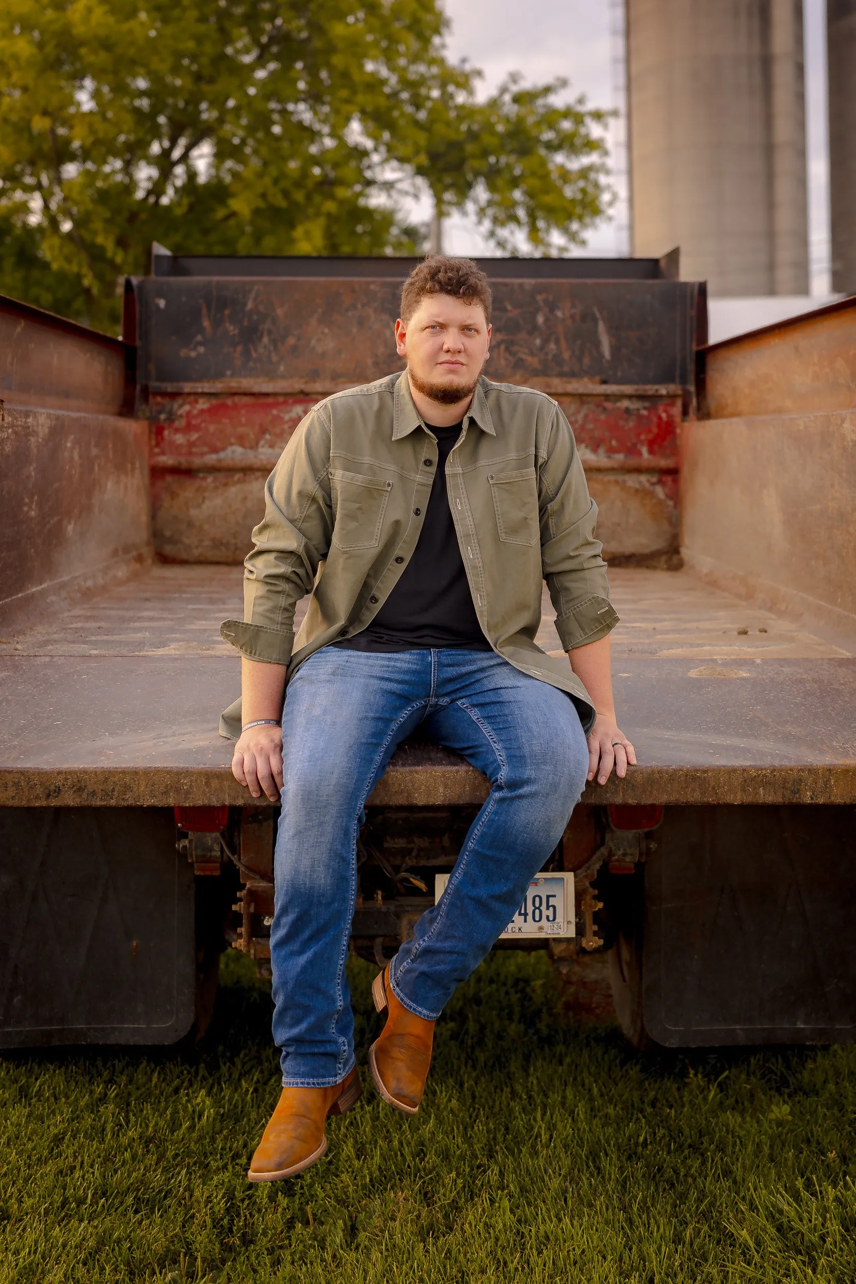 Isaac Buschur sitting on the back of a farm truck